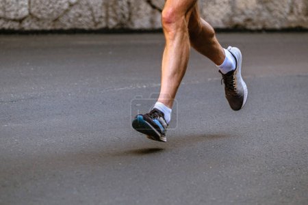 Téléchargez les photos : Jambes rapprochées coureur masculin courir sur l'asphalte gris marathon course - en image libre de droit