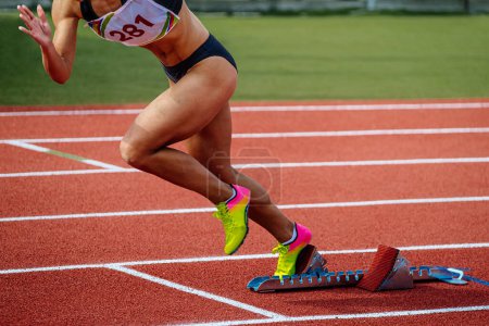 Photo for Female athlete running from starting blocks sprint race, summer athletics championships - Royalty Free Image