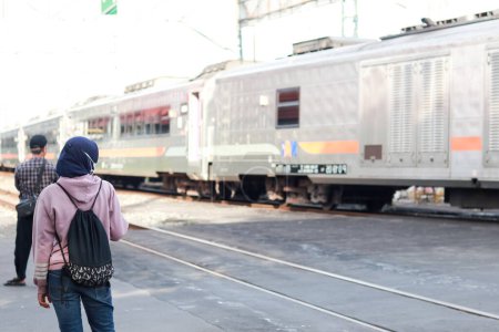 Photo for Yogyakarta, Indonesia - September 17, 2022 : a person is standing waiting for a train to pass at a railroad crossing in Yogyakarta. safety is more important. patiently waiting. - Royalty Free Image