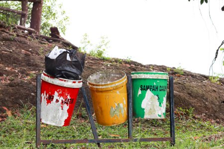 Téléchargez les photos : Jeter les ordures dans les poubelles selon la couleur. vert pour les déchets organiques, jaune pour les déchets inorganiques et rouge pour les déchets B3 ou les matières toxiques et dangereuses. - en image libre de droit