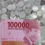 Indonesian rupiah currency. close up One hundred thousand rupiah. 100000 rupiahs. with the concept of being held by hand. receive financial assistance. white background. isolated, studio photography.