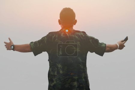 Téléchargez les photos : Double exposition, un homme portant une chemise militaire et un coucher de soleil - en image libre de droit