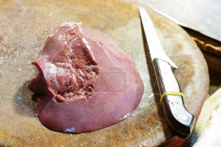 Téléchargez les photos : Foie de porc sur une planche à découper en bois avec couteau en acier inoxydable - en image libre de droit