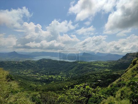Capturing an amazing panorama of a mountainous terrain covered in lush foliage and peppered with wildflowers, the shot shows a cloud-filled sky.