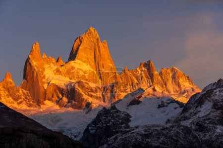 The first rays of sunlight shine on the Fitz Roy mountain, creating hues of red and orange. Fitz Roy is located near the village of El Chaltn in the Patagonia region of Argentina.