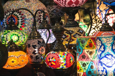 Photo for Middle Eastern lambas of different colors and sizes are hanging in the bazaar. Bright traditional Arabic and Turkish lanterns made of metal and glass, inlaid with mosaic details of different colors. - Royalty Free Image