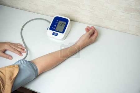 Foto de Mujer joven midiendo su presión arterial en casa. presión arterial propia y frecuencia cardíaca - Imagen libre de derechos