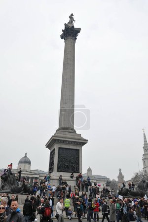 Téléchargez les photos : LONDRES - 26 MARS : Un manifestant non identifié se trouve en haut de l'une des statues de lion de la colonne Nelson à Trafalgar Square lors d'un grand rassemblement anti-coupures le 26 mars 2011 à Londres, Royaume-Uni. - en image libre de droit