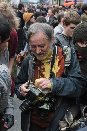Photo for A photographer cleans paint from his camera after coming under attack from a breakaway group of protesters during an anti government rally on March 26, 2011 in London, UK. Dozens of arrests were made. - Royalty Free Image