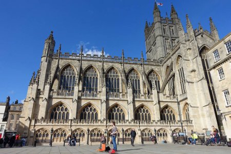 Foto de Tourists and locals enjoy a sunny day in the courtyard of the landmark Bath Abbey and Roman Baths on May 3, 2016 in Bath, UK. The historic Somerset city receives over 4 million visitors a year - Imagen libre de derechos