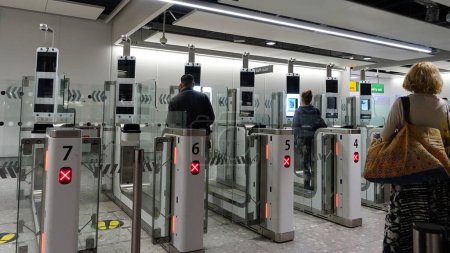 Téléchargez les photos : Londres, Royaume-Uni - 29 juillet 2018 : Les voyageurs aériens passent par des portes automatisées de contrôle des passeports à l'aéroport d'Heathrow. La Force frontalière britannique est en campagne de recrutement pour préparer le Brexit
. - en image libre de droit