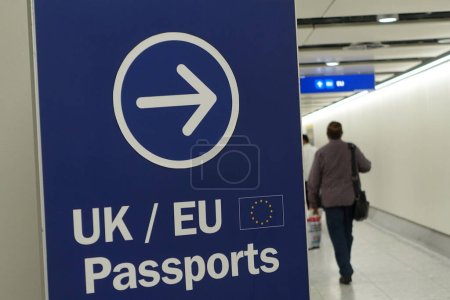 Téléchargez les photos : Affichage d'un panneau générique Royaume-Uni / UE pendant que les voyageurs aériens passent au contrôle des passeports dans un aéroport britannique - en image libre de droit