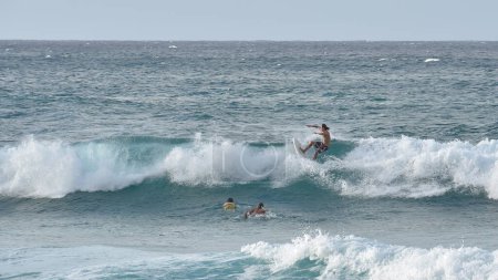 Téléchargez les photos : Vue des vagues qui s'écrasent dans l'océan avec les silhouettes des surfeurs au loin - en image libre de droit