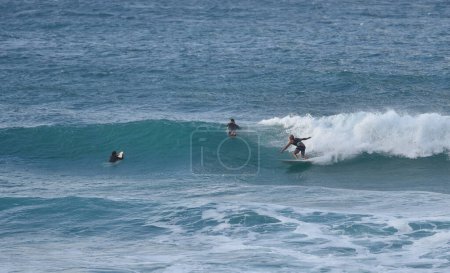 Foto de Vista de olas rompiendo en el océano con las siluetas de los surfistas en la distancia - Imagen libre de derechos