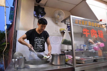 Téléchargez les photos : Le 19 juin 2015, un chef prépare des nouilles de bœuf dans un restaurant situé au bord de la rue, dans le centre-ville de Kuala Lumpur, en Malaisie. La capitale malaisienne est célèbre pour sa cuisine de rue et sa cuisine fusion asiatique. - en image libre de droit