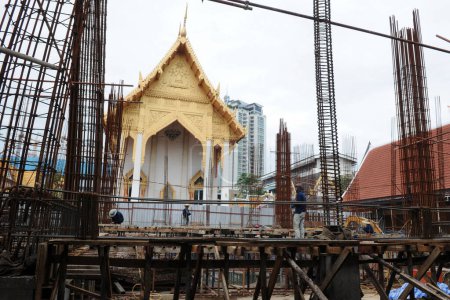 Foto de Los trabajadores trabajan en una obra de construcción en un templo budista el 16 de agosto de 2011 en Bangkok, Tailandia. La capital tailandesa es infame por su sobredesarrollo con nuevos edificios construidos en sitios históricos. - Imagen libre de derechos