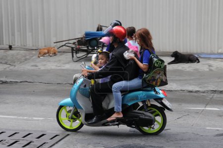 Téléchargez les photos : Les motocyclistes et les passagers roulent dans une rue du centre-ville le 16 août 2011 à Bangkok, en Thaïlande. Les motos sont souvent le moyen de transport de choix sur les routes fortement encombrées de la capitale thaïlandaise. - en image libre de droit