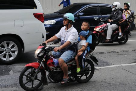 Foto de Motociclistas y pasajeros viajan en una calle del centro de la ciudad el 16 de agosto de 2011 en Bangkok, Tailandia. Las motocicletas son a menudo el transporte de elección en las carreteras muy congestionadas de la capital tailandesa. - Imagen libre de derechos