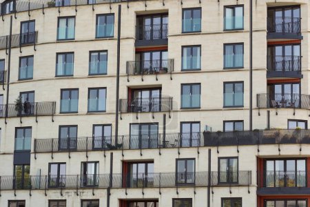 Téléchargez les photos : Vue extérieure des fenêtres et balcons d'un immeuble d'appartements de grande hauteur dans une rue d'une ville anglaise - en image libre de droit