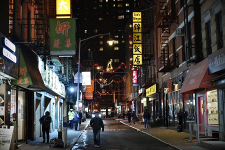 Photo for People walk along a street in Manhattan Chinatown at night on November 11, 2015 in New York, USA. - Royalty Free Image