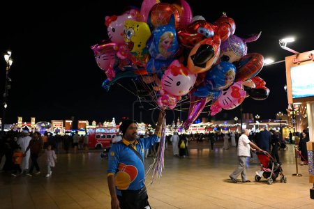 Foto de Un vendedor ambulante vende globos en una calle del centro de la ciudad el 15 de diciembre de 2023 en Dubai, Emiratos Árabes Unidos. - Imagen libre de derechos