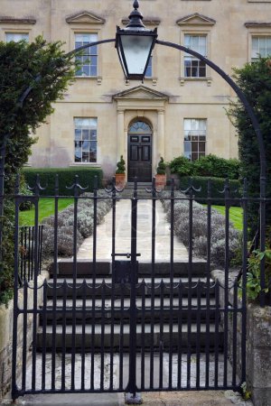Téléchargez les photos : Vue extérieure du mur de pierre environnant et porte d'entrée ornée d'une belle vieille maison de maître sur une rue dans un village anglais - en image libre de droit