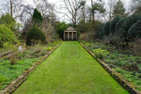 Photo for Scenic view of a lush green grass path lined by flower bed in an English Style Landscape Garden - Royalty Free Image
