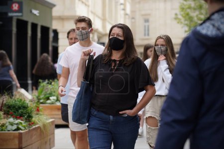 Photo for Shoppers wear face masks as a new law is introduced mandating the use of masks in shops on July 24, 2020 in Bath, UK. The wearing of face masks is to combat the Covid-19 pandemic. - Royalty Free Image