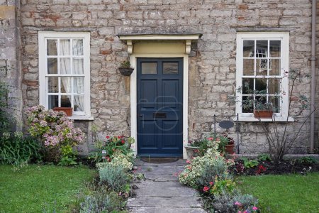 Téléchargez les photos : Vue extérieure et jardin verdoyant d'une belle maison ancienne en pierre dans une rue d'une ville anglaise - en image libre de droit