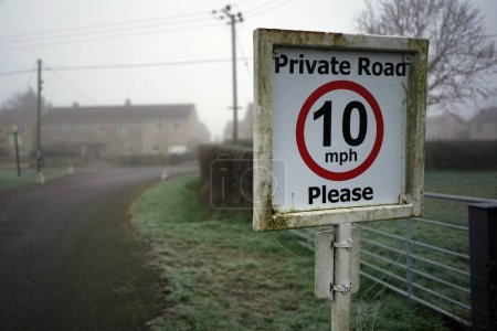 Téléchargez les photos : Vue d'un panneau générique à l'entrée d'une route privée avec une limite de vitesse de 10 mi / h - en image libre de droit
