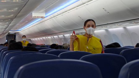 Téléchargez les photos : Un agent de bord de Lion Air portant un masque donne une démonstration de sécurité avant vol le 3 février 2020 à Bangkok, Thaïlande. Le personnel de la compagnie aérienne porte régulièrement des masques faciaux en raison de la pandémie de covide-19. - en image libre de droit