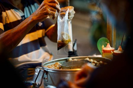 Traditionelle indonesische Frikadellen-Straßenhändler bereiten in der Nacht Bestellungen für den Kunden vor