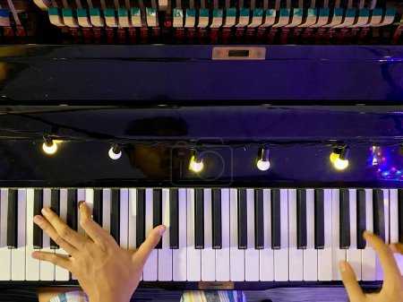 Blick von oben auf schwarz glänzendes klassisches Piano mit Pianistenhand im Rahmen