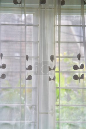 Un rideau semi-transparent (vitrase) avec un motif floral minimaliste