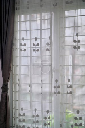 Un rideau semi-transparent (vitrase) avec un motif floral minimaliste