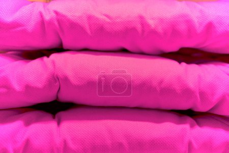 Pink chair cushion foam stacked with one another.