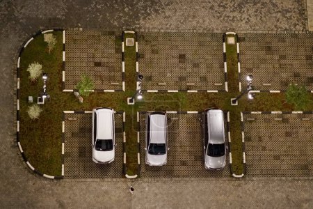 An apartment outdoor parking space filled with 3 cars parralel to each other.