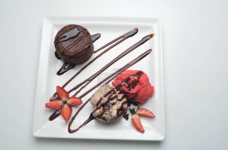 Chocolate fondant cake, molten lava cake with strawberry and vanilla ice cream scoop and fresh berries on plate.