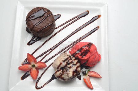 Chocolate fondant cake, molten lava cake with strawberry and vanilla ice cream scoop and fresh berries on plate.