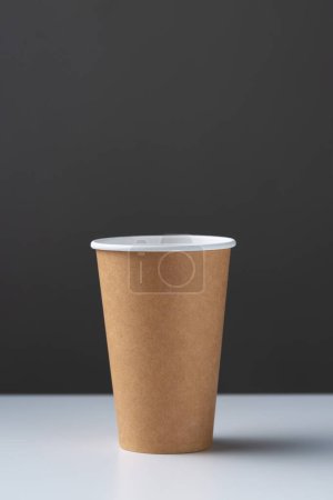 Foto de Disposable cardboard biodegradable glass on a white table, gray background. - Imagen libre de derechos