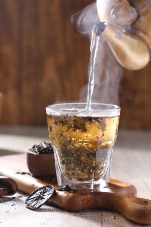 Foto de Vaso de té caliente con cubitos de hielo sobre fondo de madera - Imagen libre de derechos