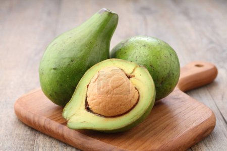 Foto de Avocado fruit on a wooden cutting board on the kitchen table - Imagen libre de derechos