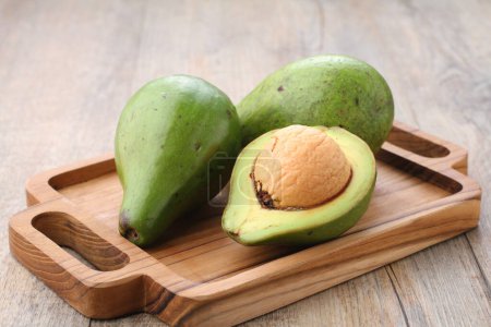 Foto de Avocado fruit on a wooden cutting board on the kitchen table - Imagen libre de derechos