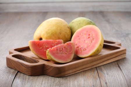 Téléchargez les photos : Slices of red guava on a wooden cutting board on the dining table - en image libre de droit