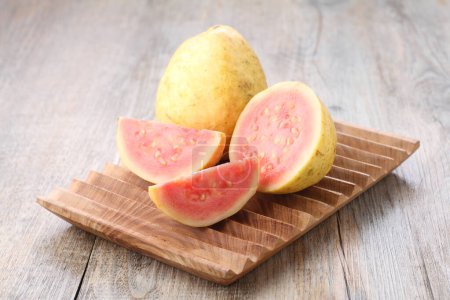 Foto de Slices of red guava on a wooden cutting board on the dining table - Imagen libre de derechos
