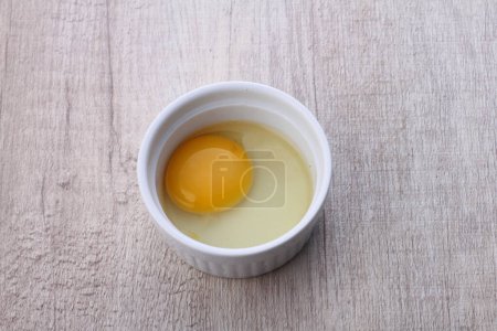 Photo for Egg yolk in a bowl on a wooden background - Royalty Free Image