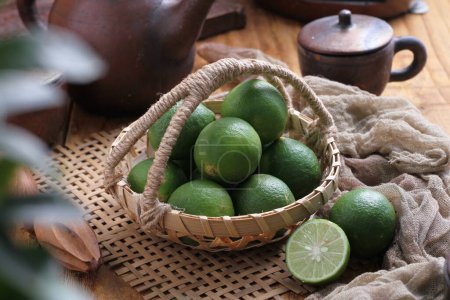 Téléchargez les photos : Fresh green and lime in a basket on a wooden background - en image libre de droit