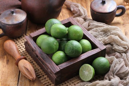 Photo for Fresh green and lime fruits in a wooden bowl on a rustic background - Royalty Free Image