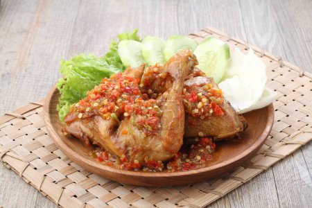 Foto de Ayam penyet  is Indonesian fried chicken dish consisting of fried chicken that is smashed with the pestle against mortar to make it softer, served with sambal, slices of cucumbers, fried tofu and tempeh. - Imagen libre de derechos