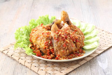 Téléchargez les photos : Ayam penyet est plat de poulet frit indonésien composé de poulet frit qui est écrasé avec le pilon contre le mortier pour le rendre plus doux, servi avec sambal, tranches de concombres, tofu frit et tempeh. - en image libre de droit